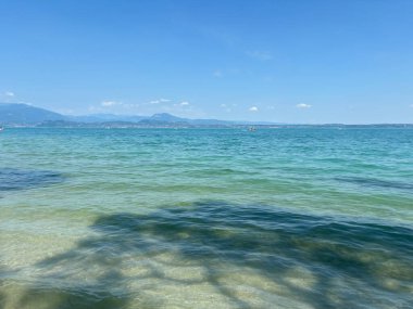 Hardy Gölü 'nün masmavi su yüzeyi ufuktaki uzak mavi tepelerle çevrili güneşli mavi gökyüzüne karşı..