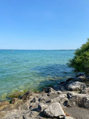 Sahil şeridinin manzarası Gardy Gölü 'nün sakin dalgalarıyla yıkanan büyük ve keskin taşlarla kaplıydı..