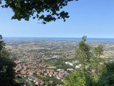 Kale kulesinin tepesinden San Marino 'daki evlerin kırmızı çatılarıyla kaplı dağ yamacının manzarası. 