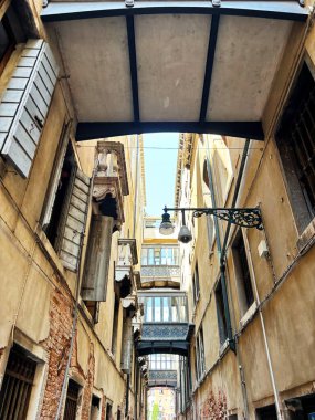 Antik Venedik 'in dar su sokaklarında bir gondol gezintisi neredeyse birbirine bastırıp gökyüzünü engelleyen evler arasında..