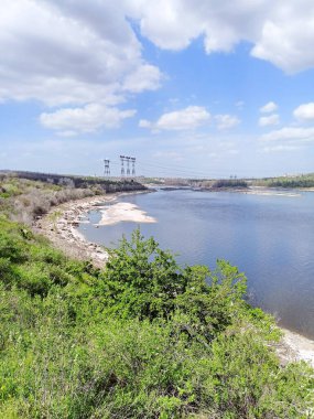 Dinyeper 'in Khorytsia kıyılarının panorama' sı güneş ışınlarının altında ufuktaki barajın ve elektrik hatlarının arka planına karşı..