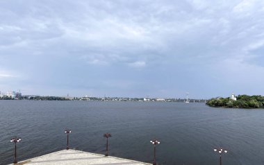 Dinyeper 'ın geniş kanalı boyunca uzanan panorama, bulutlu bir yaz gününde Dnipro şehrinin binalarıyla kaplı, zar zor görülebilen karşı kıyının arka planına karşıdır..