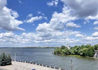 Dinyeper şehir setinin tepesinden Dinyeper 'in geniş mavi yüzeyi ve ufkun ötesinde süzülen kar beyazı bulutların arka planıyla çevrili panorama..