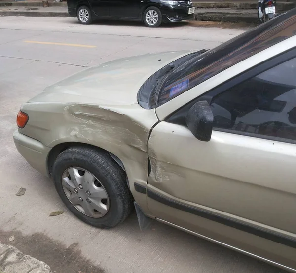 Gold color car\'s dent beside left wheel from an accident.