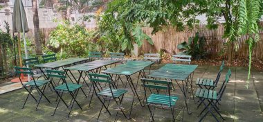 Doğal ortamda çimento zemine boyanmış ahşap masalar ve sandalyeler koyun..