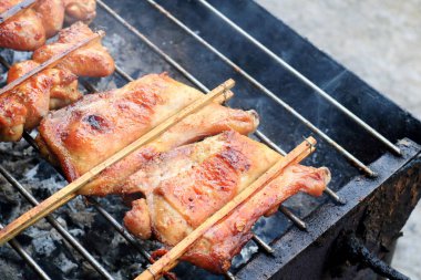 Tavuk budu ve bacağı klemplenmiş bambu çubuğu retro tarzı sobayı dumanla kızartıyor, Tayland.