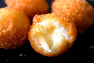 Isırılmış peynir topu siyah arka planda açık peynir yığını..