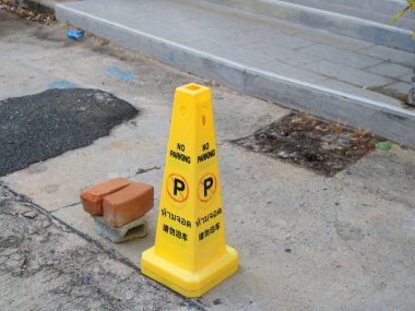 Tayland 'da caddede sarı plastik trafik konisi ve ağaç dilinde parkedilmemiş Tayland ve Japonca