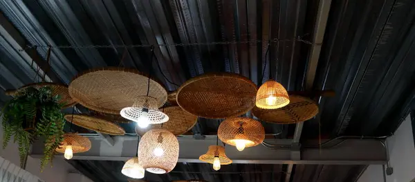 stock image Group variety shape bamboo native Thai style weaving cover lamp hanging on dark gray wave shape metal ceiling in Thailand.