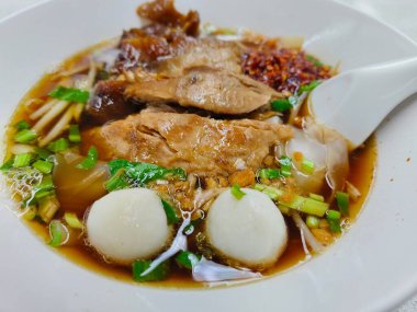 Beş baharatlı domuz etli şehriye, beyaz kasede ve beyaz kaşıkla yakından görülüyor..