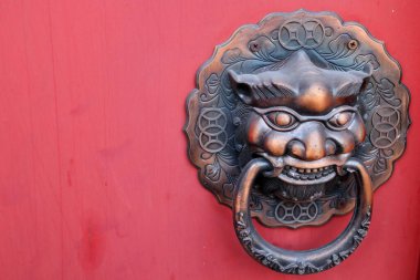 Tayland 'da kırmızı boyalı ahşap kaplama üzerinde antik yerli baş şekli pirinç kapı tokmağı.