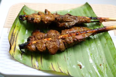 İki bambu çubuğunu kapat. Tavuk ciğerini masada muz yaprağında kızart..