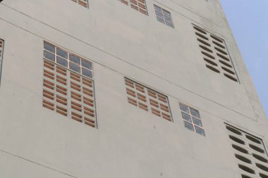 Tayland 'daki beyaz binanın duvarında cam bloklar ve beton kanallar var..