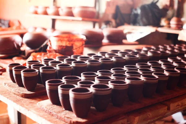 Çömlek, seramik ve el yapımı ürünler bir atölye ve galeride rafta. Bir el sanatları mağazasında sergilenen kilden vazoları ve toprak malzemelerini kapatın. Küçük bir işletmedeki bitmiş kil eşyasının çeşitliliği