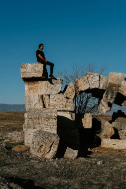 Genç yakışıklı gezgin bulutsuz mavi gökyüzünün altında antik Laodicea şehrini keşfediyor.