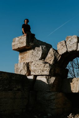 Genç yakışıklı gezgin bulutsuz mavi gökyüzünün altında antik Laodicea şehrini keşfediyor.