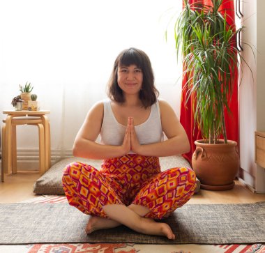 Genç beyaz kadın evde yoga yapıyor.