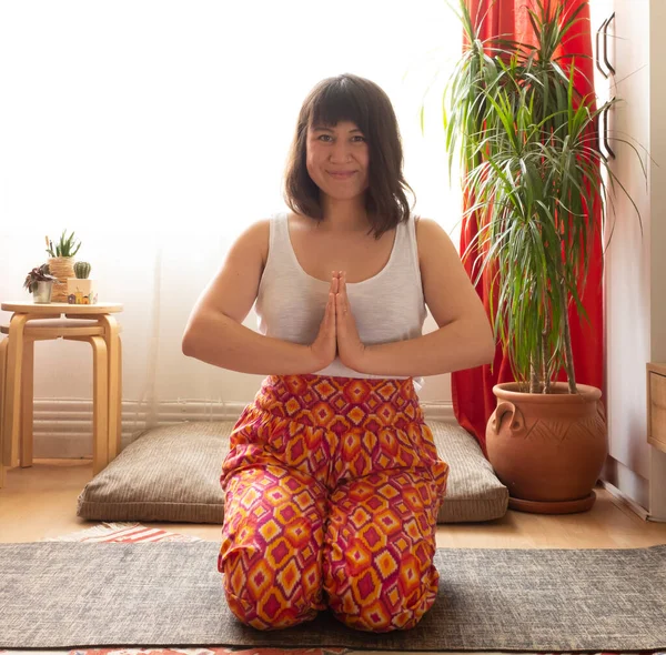 Genç beyaz kadın evde yoga yapıyor.