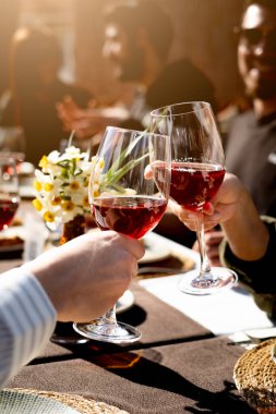 Arkadaşlar akşam yemeğinde kadehlerini şarap ile kaldırıyorlar, dikey, yakın plan.