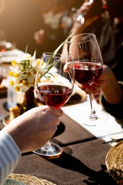 Arkadaşlar akşam yemeğinde kadehlerini şarap ile kaldırıyorlar, dikey, yakın plan.