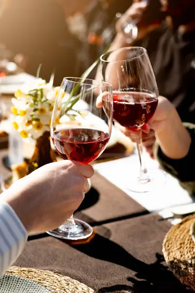 Arkadaşlar akşam yemeğinde kadehlerini şarap ile kaldırıyorlar, dikey, yakın plan.
