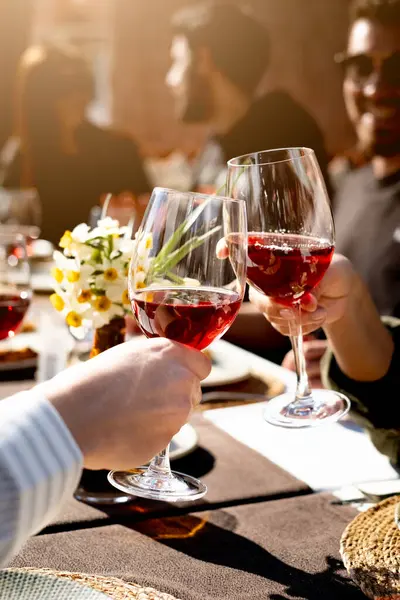 Arkadaşlar akşam yemeğinde kadehlerini şarap ile kaldırıyorlar, dikey, yakın plan.