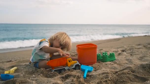 クローズアップは ビーチでシャベルで砂の中で遊んでいる子供 高品質4K映像 — ストック動画