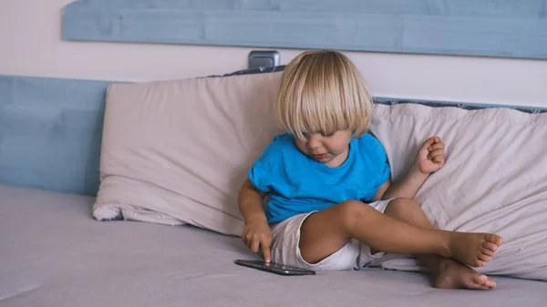 small child playing smartphone on the bed. High quality 4k footage