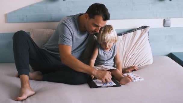Pequeno Menino Caucasiano Com Seu Pai Cama Desenhar Com Lápis — Vídeo de Stock