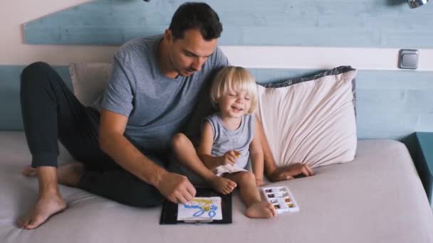 ベッドの上の父親と一緒に小さな白人の少年は 色鉛筆で描く 高品質4K映像 — ストック動画