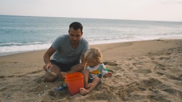一个小孩和他的父亲在海滩用铲子和桶玩的特写镜头 高质量的4K镜头 — 图库视频影像
