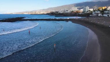 Atlantik okyanusu olan Tenerife adasındaki dalgaların ve plajın tadını çıkaran turistlerin hava manzarası. Yüksek kaliteli FullHD görüntüler
