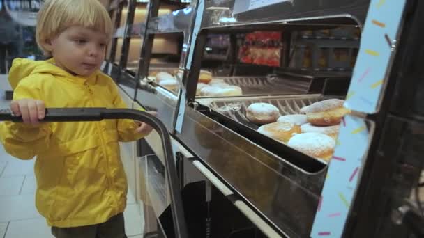 Little Blond Boy Supermarket Points His Finger Donut Licks His — Wideo stockowe