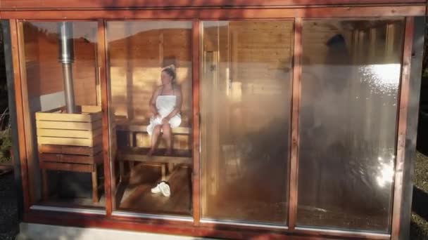 Young Woman Wrapped White Towel Sitting Sauna Panoramic Window High — Stockvideo