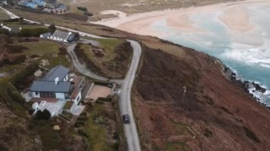 A drone follows a car driving down the road along the Barley Cove beach in Mizen Head. High quality 4k footage