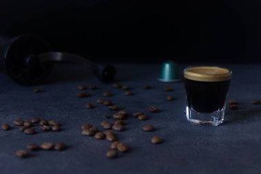 bir fincan kahve ve bir kapsül, kahve çekirdekleri koyu arkaplana dağılmış, üst görünüm, seçici odak, kopyalama alanı