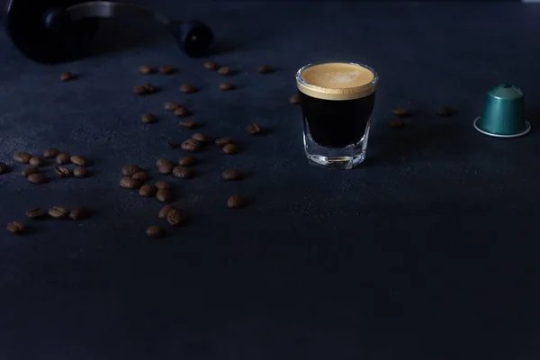 coffee and a capsule, coffee beans scattered on a dark ground, top view, selective focus, copy space