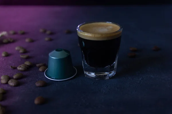 a cup of coffee and a capsule, coffee beans scattered on a dark ground, top view, selective focus, copy space