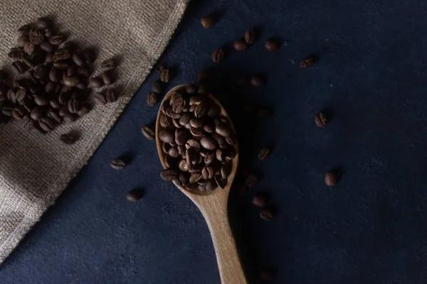 stock image Top view photo of a spoonful of coffee beans on a dark background or surface, selective focus, copy space 