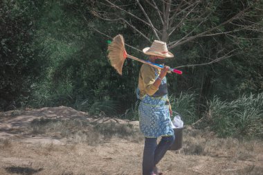Pattaya, Tayland - 19 Aralık 2022 Wonderfruit festivali sırasında Asyalı bir kadın işçi, süpürgesi olan, seçici odaklı Asyalı bir kadın.