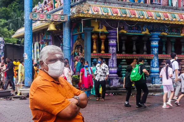 Batu Mağaraları, Kuala Lumpur, Malezya - 24 Ocak 2023: Batu Mağaraları 'nda maske ve turuncu tişört giyen yaşlı bir adamın portresi. Geleneksel bir Hindu hayranı..