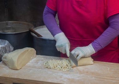 Eller kesme tahtasındaki hamuru bıçakla kesiyor. Kalguksu, Gwangjang Market, Seul, Güney Kore 'de geleneksel Kore biçimli buğday unlu erişte..