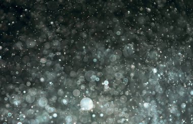 Koyu arkaplanda parlayan ışık parçacıkları soyut doku oluşturur