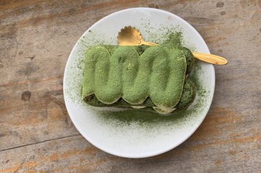 Tiramisu matcha ahşap bir masada servis edilir.