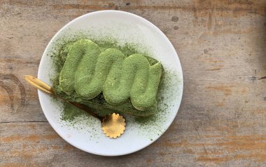 Tiramisu matcha ahşap bir masada servis edilir.