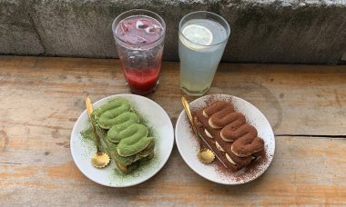 Çilekli soda, limonlu soda, çikolatalı tiramisu ve kibrit, ahşap bir masada servis edilir.