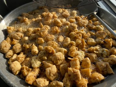 street food fried tofu meatballs in a frying pan with hot oil clipart