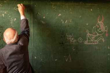 Okulda öğretmen tahtaya yazı yazıyor, komik bir resim.