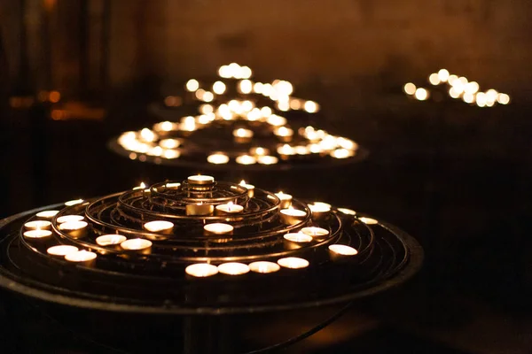 many fired candles in the church on a stand