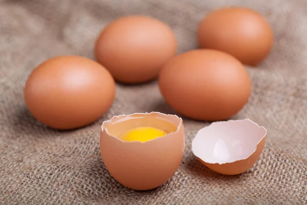 stock image Fresh eggs on sacking, broken eggshell, yolk